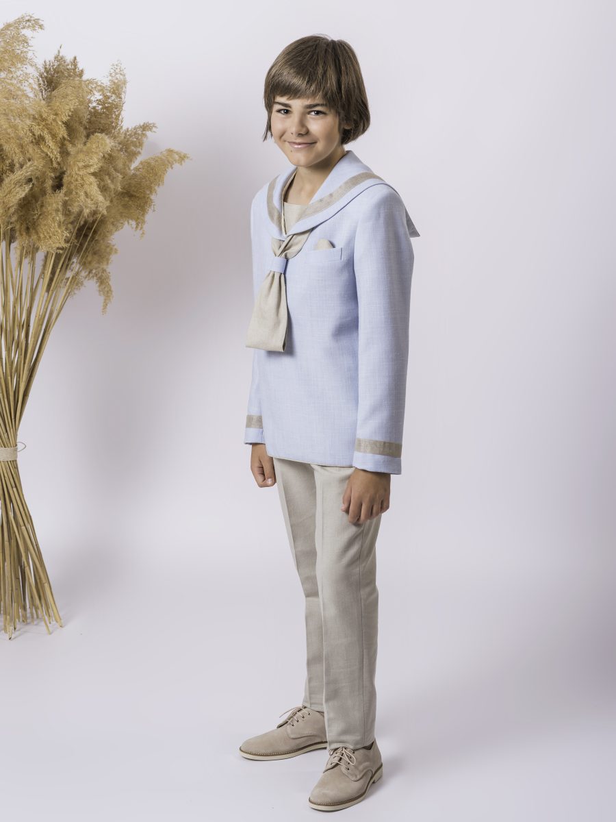 Conjunto marinero de comunión con blusa azul celeste, cuello y corbata beige champán y pantalón beige, mostrado de lado para apreciar los puños.
