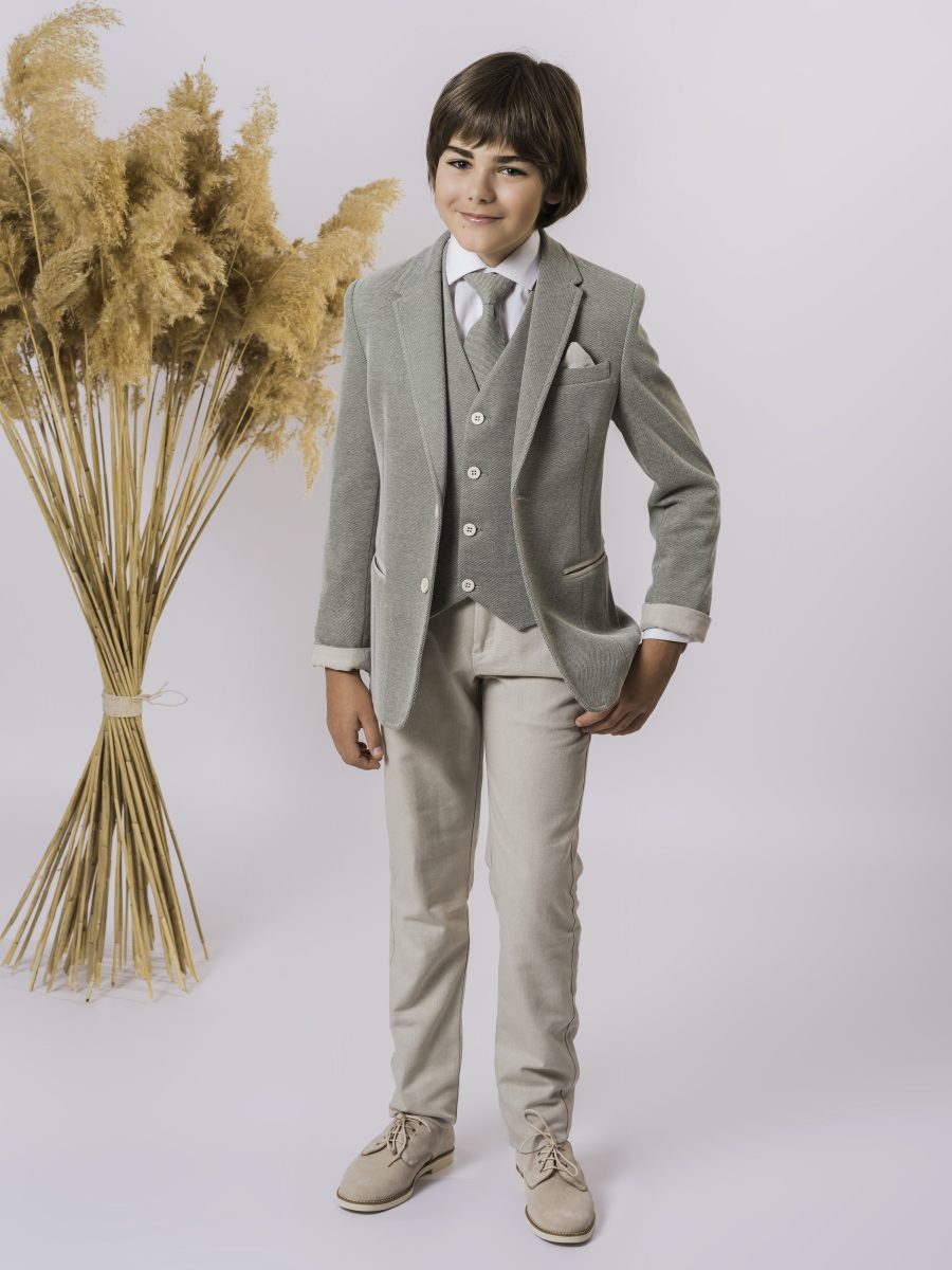 Conjunto de comunión con chaqueta y chaleco verde salvia, solapas clásicas, camisa blanca y corbata gris, combinado con un pantalón beige.
