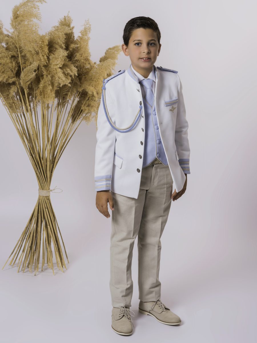 Traje de comunión con chaqueta blanca militar, cordón y chaleco azul celeste, insignia en el pecho y pantalón beige como contraste claro.
