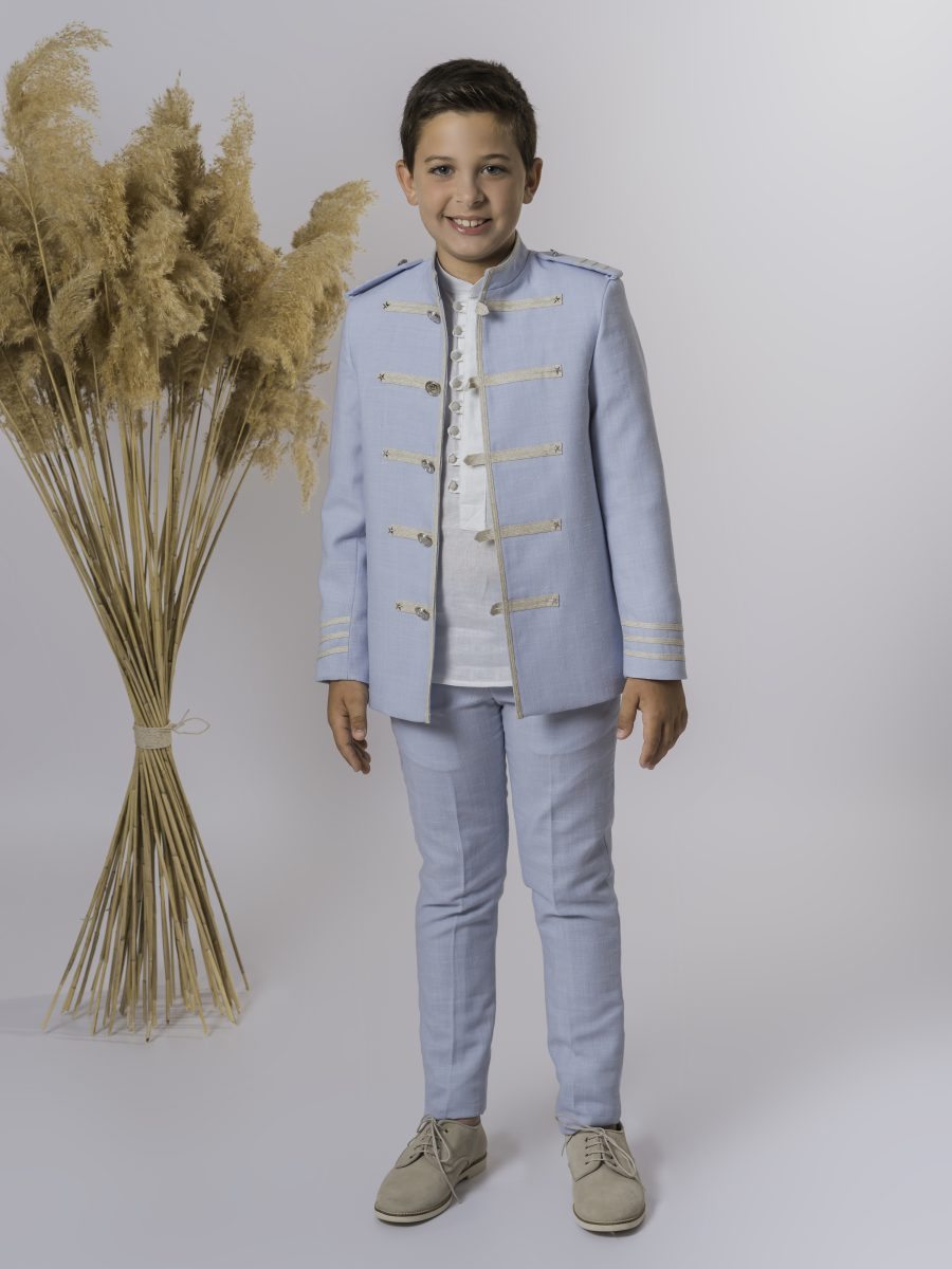 Traje de comunión azul celeste con chaqueta militar adornada por galones dorados diagonales, botones metálicos y camisa blanca sobre pantalón del mismo azul.