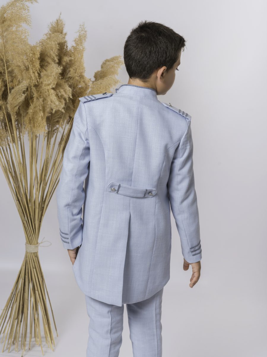Espalda de una chaqueta de comunión azul celeste con faldones y trabillas en la cintura, acompañada por pantalón azul y galones dorados en los puños.
