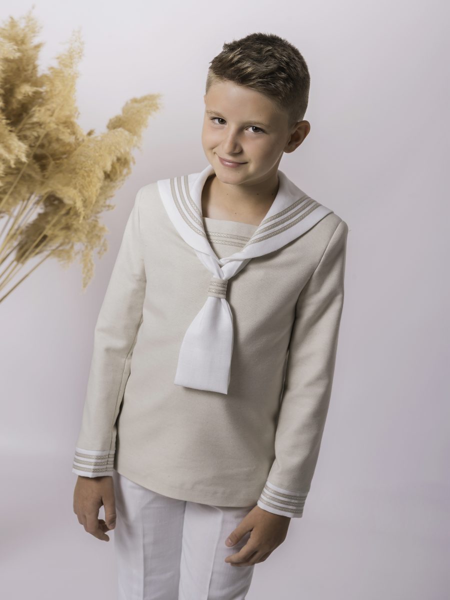 Detalle de blusa marinera de comunión beige champán con cuello blanco, lazo blanco y un galón decorativo que destaca en el puño.