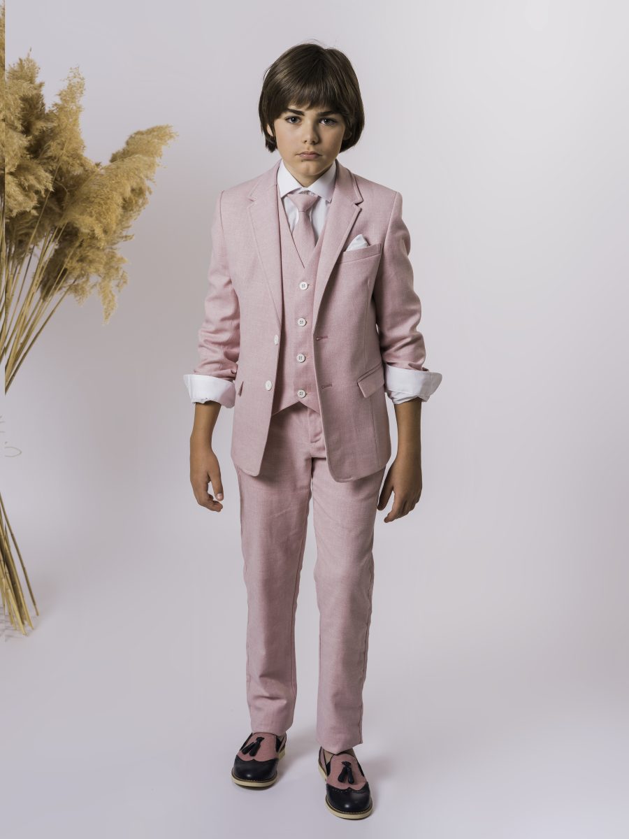 Traje de comunión de tres piezas rosa empolvado, con chaleco y pantalón a juego, camisa blanca, corbata rosa y pañuelo en el bolsillo.
