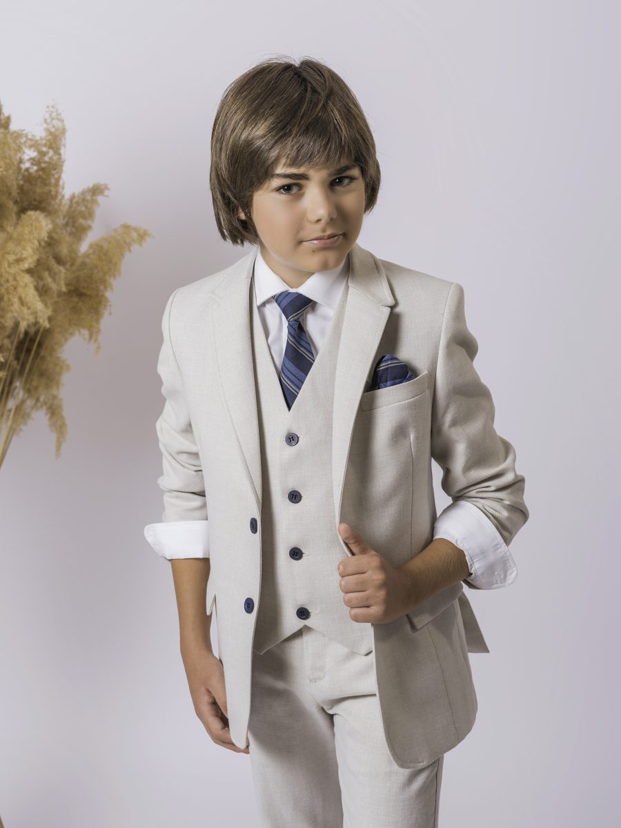 Detalle de traje de comunión beige arena con chaleco a juego, botones azul marino, camisa blanca y corbata azul de rayas.