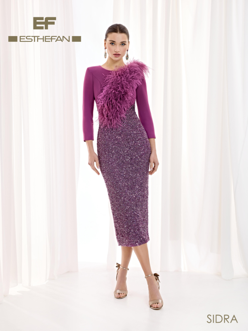 Vestido midi de Esthefan con cuerpo lila fucsia, falda violeta de lentejuelas y plumas moradas en un hombro junto al escote redondo.
