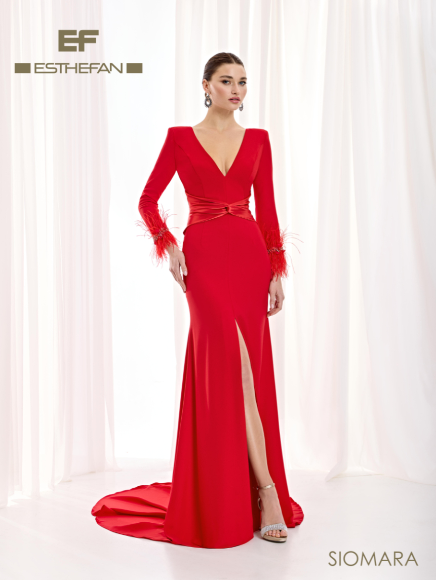 Vestido rojo de Esthefan de silueta sirena, con escote en V, faja satinada cruzada, plumas en los puños y abertura frontal.