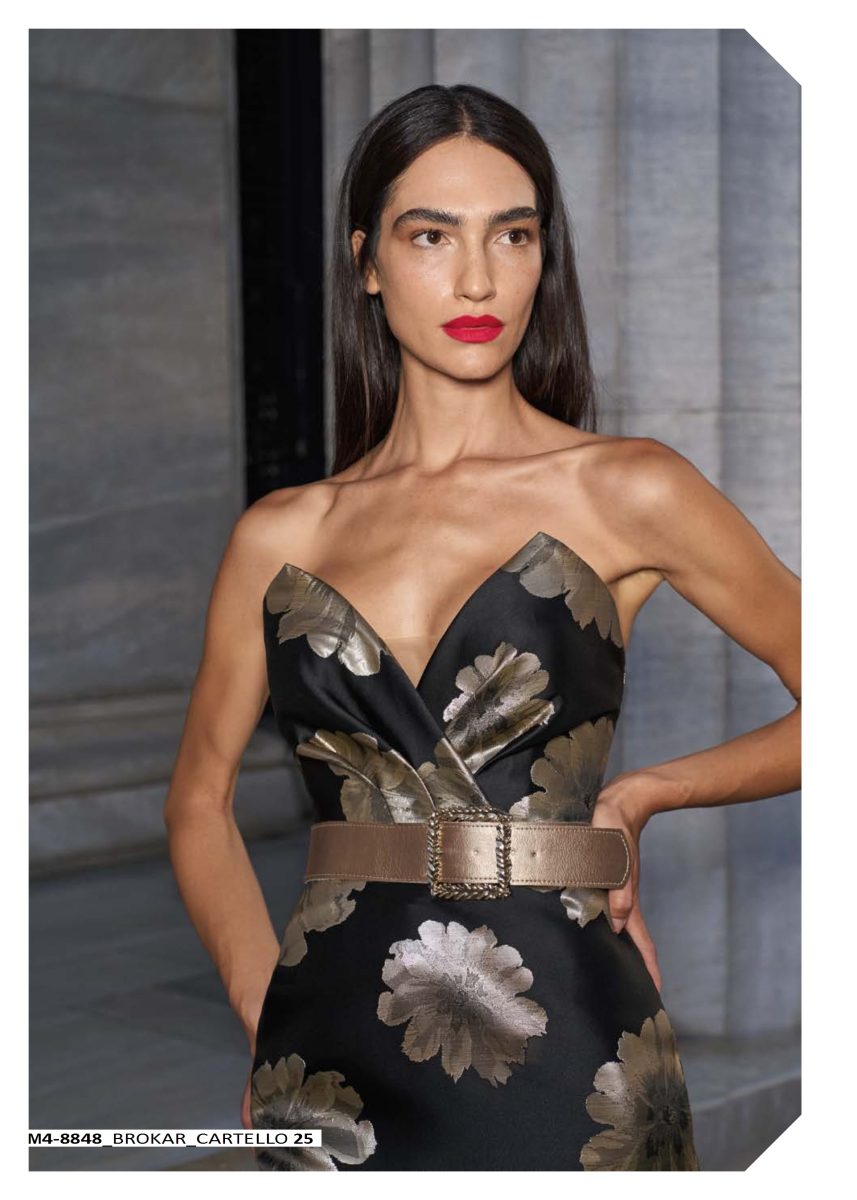 Detalle del escote en V del vestido negro de Mischalis, con estampado floral dorado y cinturón tostado que marca la cintura.