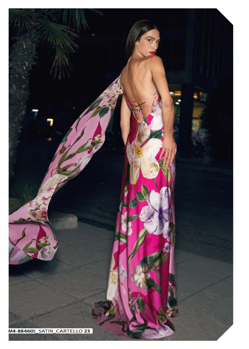 Espalda abierta del vestido estampado de Mischalis con tirantes cruzados y larga caída de tejido floral en tonos rosas desde un hombro.